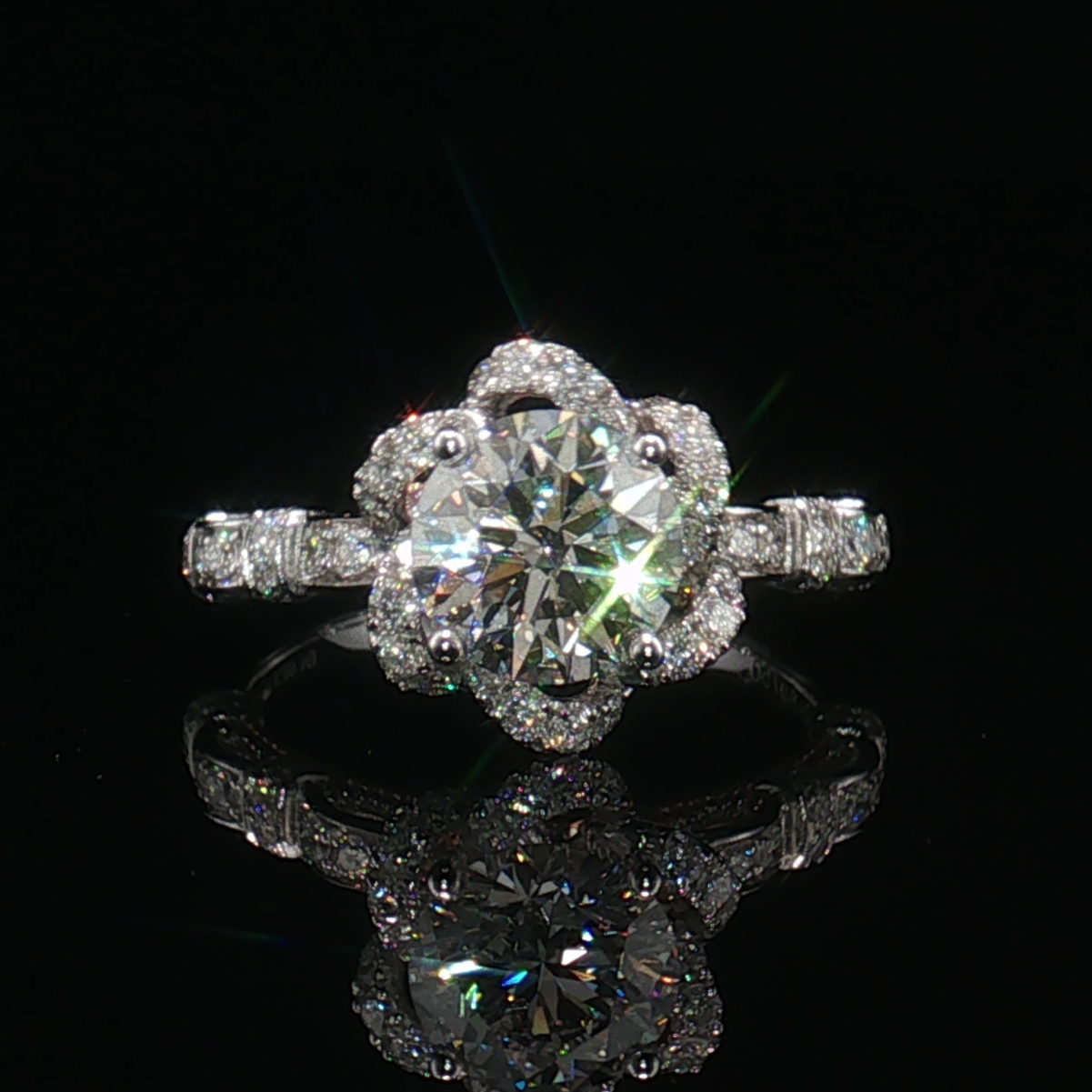 Front view of a round centre stone ring with a scalloped floral halo and pavé shoulders