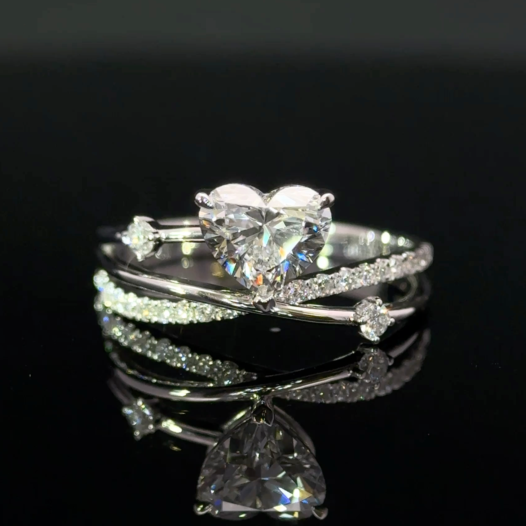 Close-up front view of a heart-shaped centre stone framed by crossing pavé and polished bands