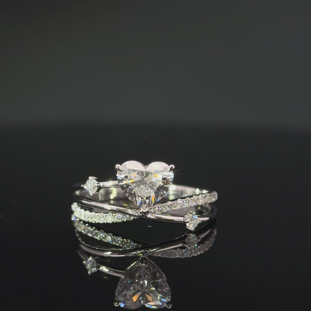 Heart-shaped centre stone ring with layered curved bands on a reflective black surface